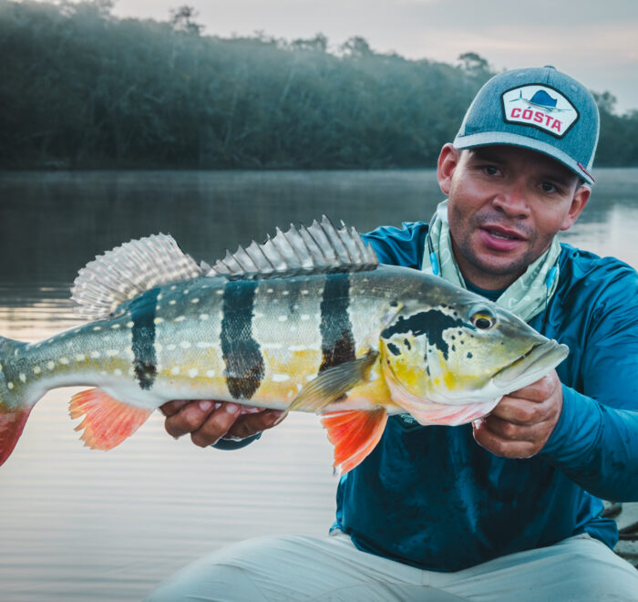 Angler proudly holding a Peacock Bass caught on the Orinoco River. Discover and book your luxury fishing adventure with Fishing ByEcolodge in Colombia.