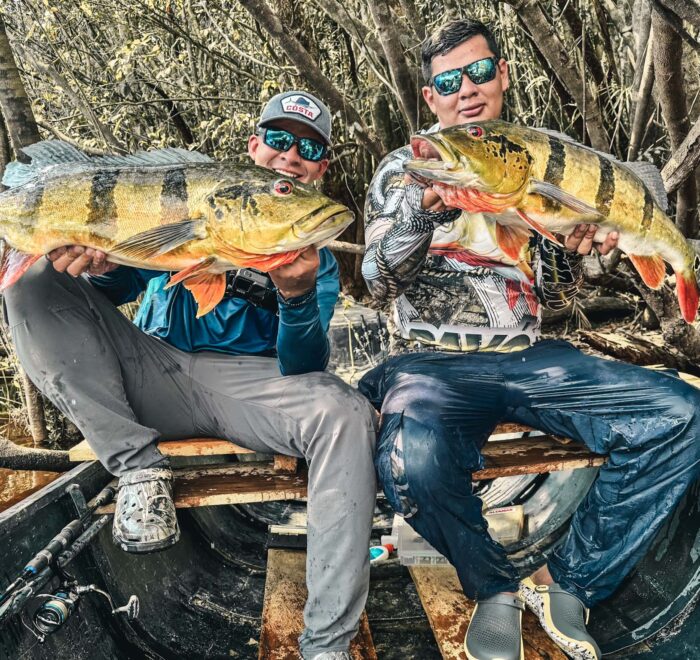 Two anglers proudly showcasing their Peacock Bass catches. Experience the thrill of catching your own—book your luxury fishing trip in Colombia today!